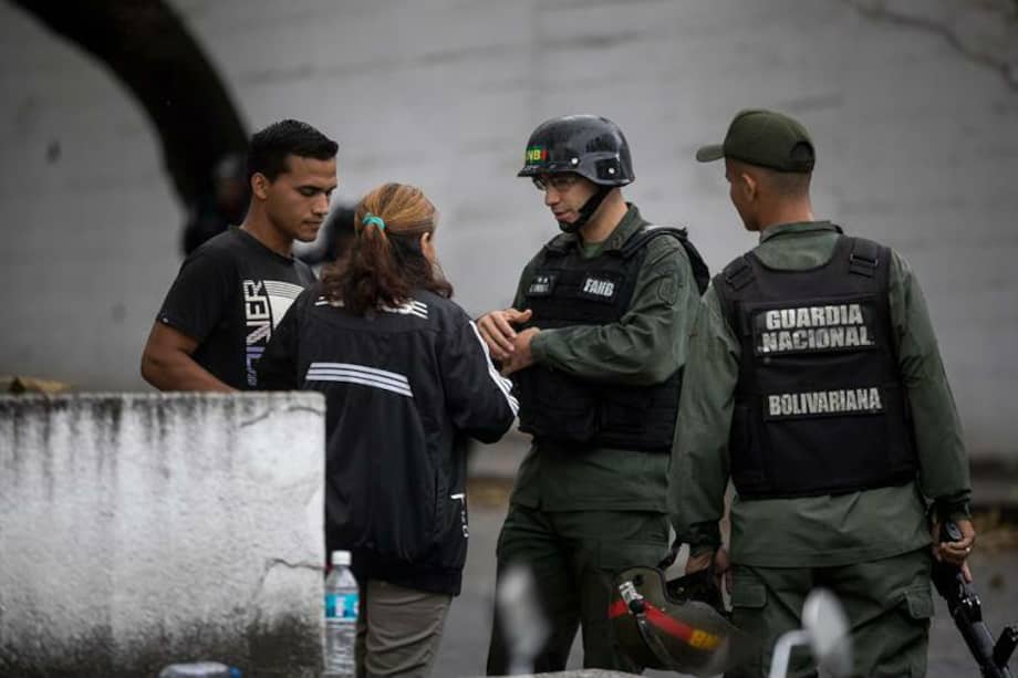 Dany Pérez Cisneros y Zoraida Cisneros, madre y hermano de uno de los detenidos durante la operación de este lunes donde murió Óscar Pérez, hablan con agentes de la Guardia Nacional. / EFE