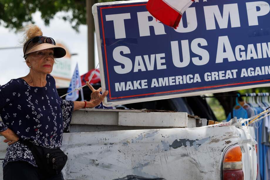 Una partidaria del expresidente estadounidense Trump se encuentra junto a un cartel que dice "Trump nos salva de nuevo: haz que Estados Unidos vuelva a ser grande", mientras ella y otros se reúnen antes de conducir una caravana hacia Mar-a-Lago en apoyo a Trump, en Miami, Florida. , EE. UU., 14 de julio de 2024.