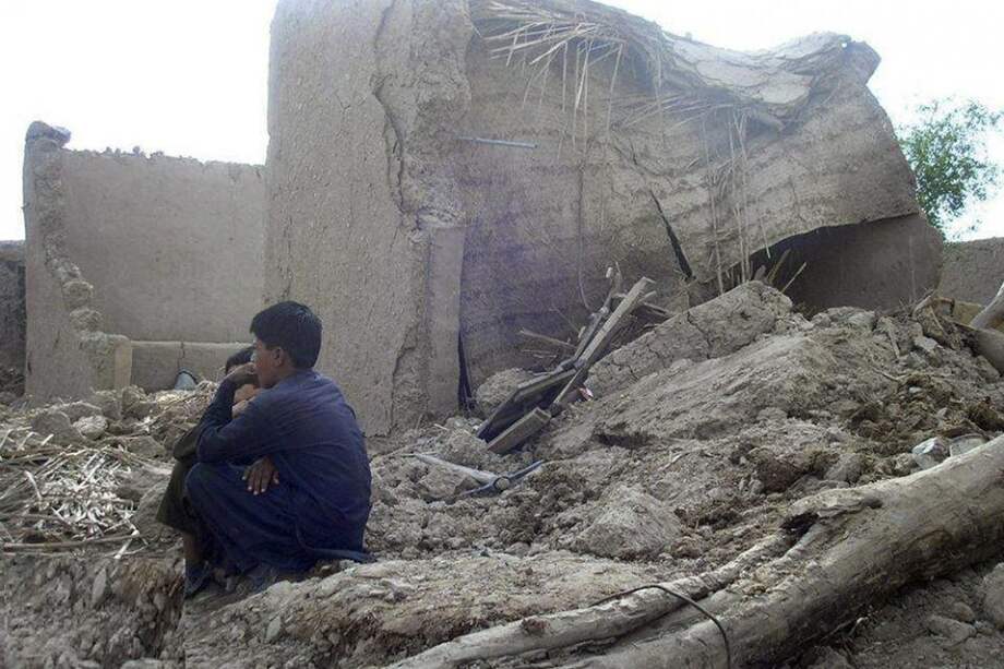 Varias personas permanecen junto a sus casas en ruinas tras el terremoto en Awaran (Pakistán)./ EFE