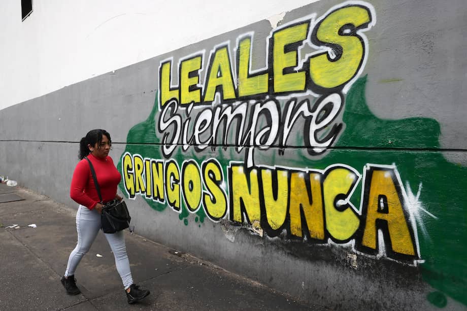 Una mujer camina frente a un mural en Caracas, Venezuela, que dice: "Leales siempre, gringos nunca".