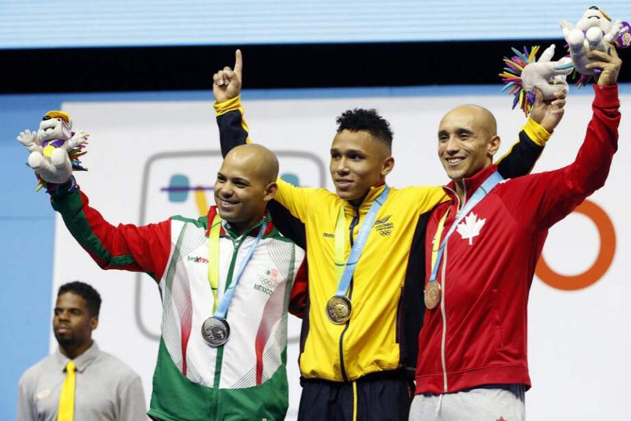 Las atletas de Colombia, México y Canadá, Luis Mosquera (c), Bredni Roque (i) y Francis Luna-Grenier, tras recibir respectivamente las medallas de oro, plata y bronce en la categoría masculina de 69kg de levantamiento de peso. Foto: EFE