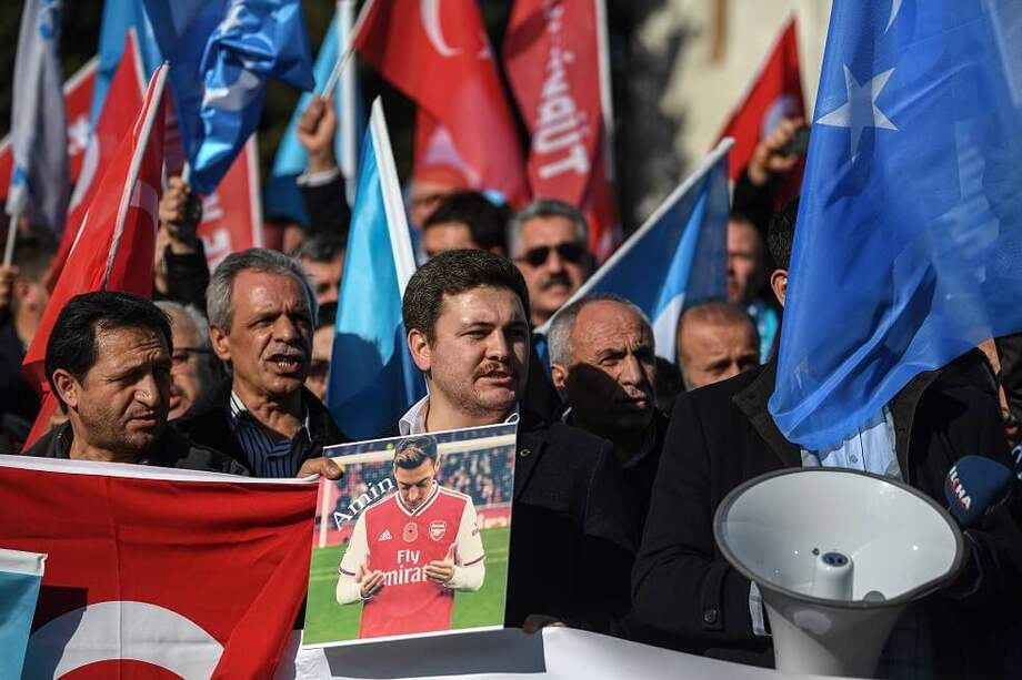 Un partidario de la minoría musulmana uigur de China sostiene una pancarta del mediocampista alemán de origen turco del Arsenal, Mesut Ozil, junto a las banderas del Turquestán Oriental durante una manifestación en la plaza Beyazid en Estambul el 14 de diciembre de 2019. / AFP