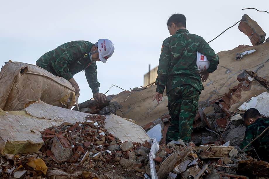Rescatistas de Vietnam caminan este martes sobre escombros de edificaciones destruidas en Catia La Mar, La Guaira (Venezuela).