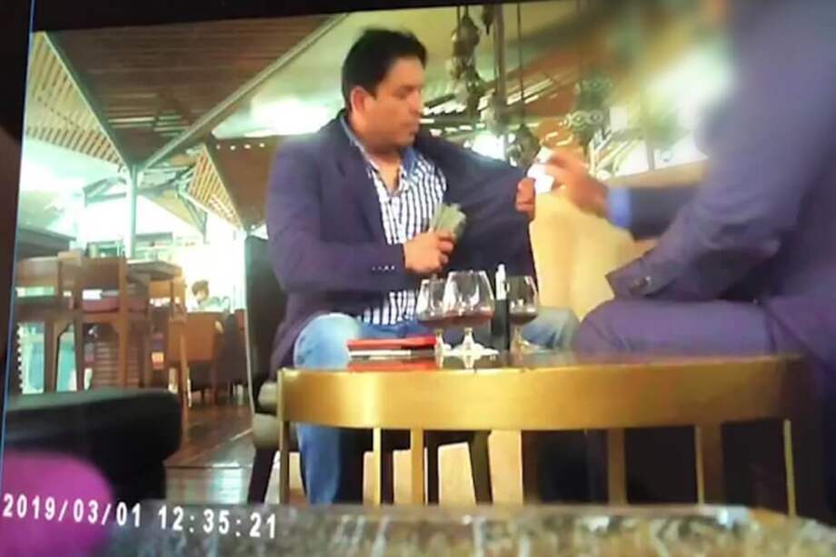 En la imagen de un video de la Fiscalía se ve al fiscal de la JEP Carlos Bermeo recibiendo un fajo de dinero y guardándolo en su chaqueta.
/ Fiscalía.