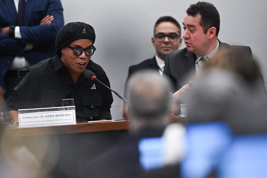 El exfutbolista brasileño Ronaldinho Gaúcho (izq.) declaró ante una comisión de la Cámara de Diputados de Brasil que investiga fraudes con pirámides financieras, en la sede del Congreso en Brasilia (Brasil).