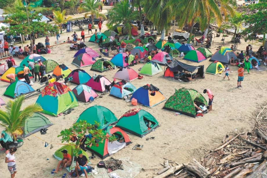 Migrantes varados acampan en una playa mientras esperan subirse a un bote en Necoclí, para cruzar a la vecina Panamá y continuar su viaje hacia Estados Unidos.