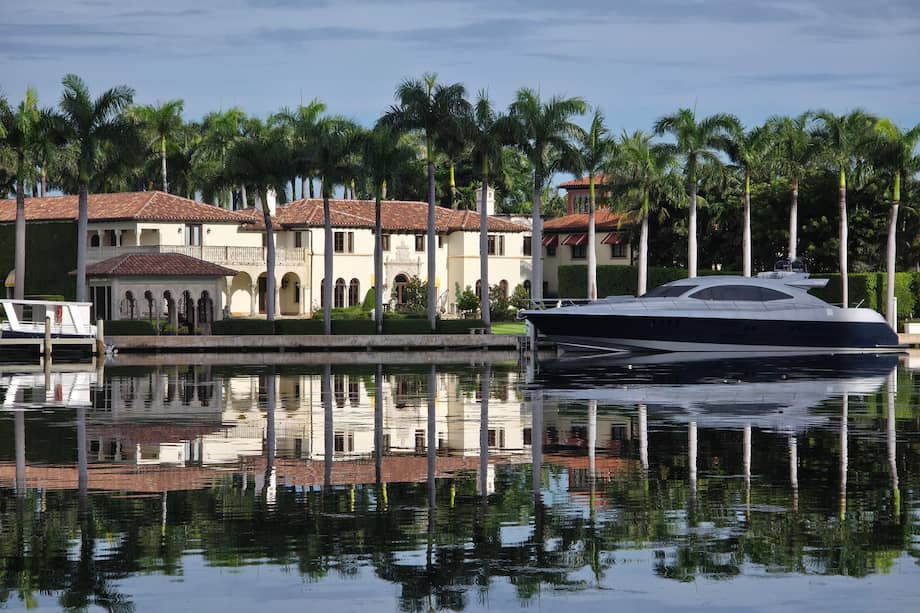 Fotografía de un yate frente a casas en el área de Miami Beach, en Miami (Estados Unidos). Más de 13.200 ultrarricos, aquellos con fortunas superiores a los 30 millones de dólares, tienen una vivienda secundaria en Miami, más que en ninguna otra parte del mundo.