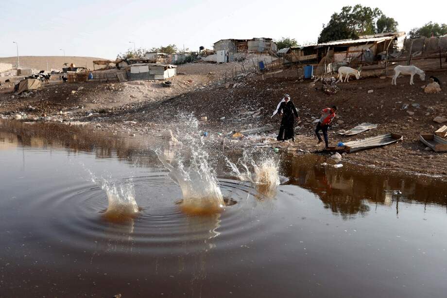 Dos hombres lanzan piedras a un estanque en la comunidad beduina de Jan al Ahmar, entre la ciudad cisjordana de Jericó y Jerusalén. / EFE