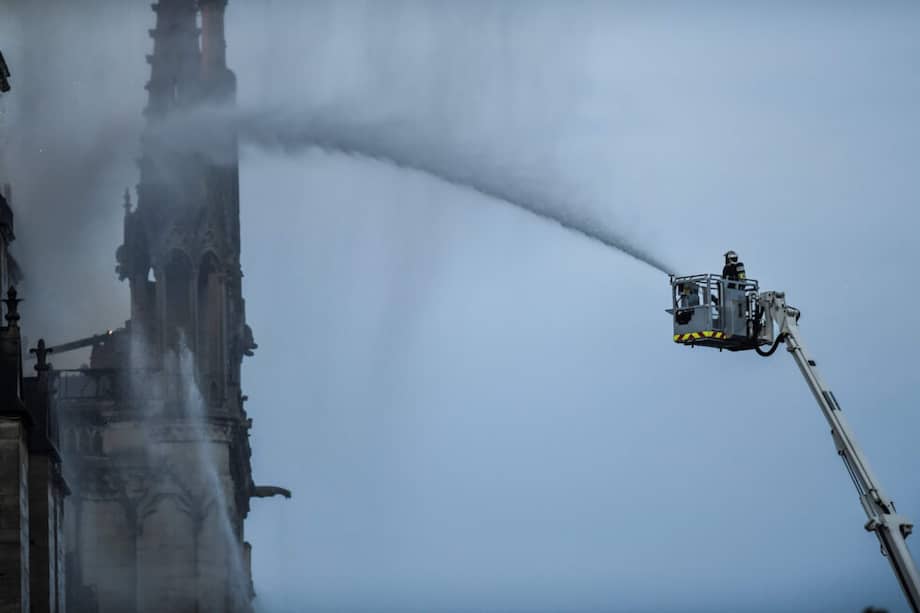 Un bombero intenta controlar las llamas que consumieron parte de la catedral de Notre Dame, en París, el lunes. / AFP