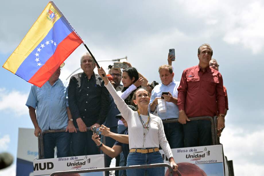 La líder opositora venezolana, María Corina Machado (C), ondea una bandera nacional junto los líderes de Unidad Venezuela: Delsa Solorzano, Alfredo Ramos, César Pérez Vivas, Juan Pablo Guanipa y Biagio Pilieri.