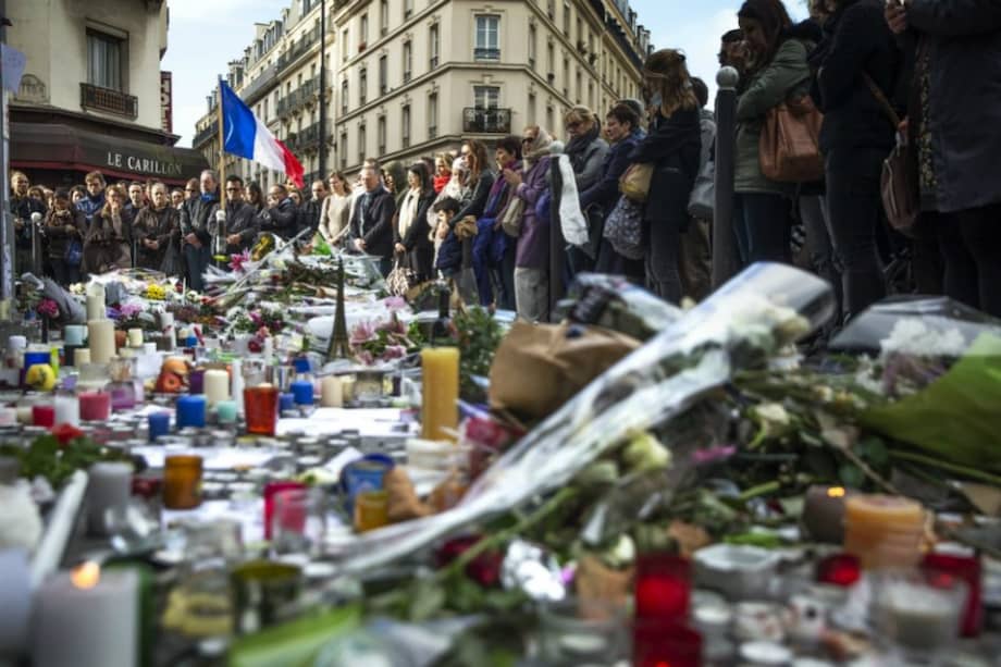Numerosas personas guardan un minuto de silencio como homenaje a las víctimas de los atentados del viernes en la capital francesa ante el bar le Carillon de París. / EFE