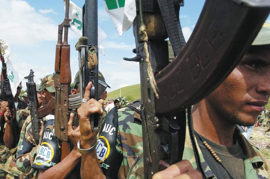 Miembros de las AUCs sostienen sus rifles durante una ceremonia de deposición de armas en la vereda Otu, en el municipio de Remedios (Antioquia), en diciembre de 2005.