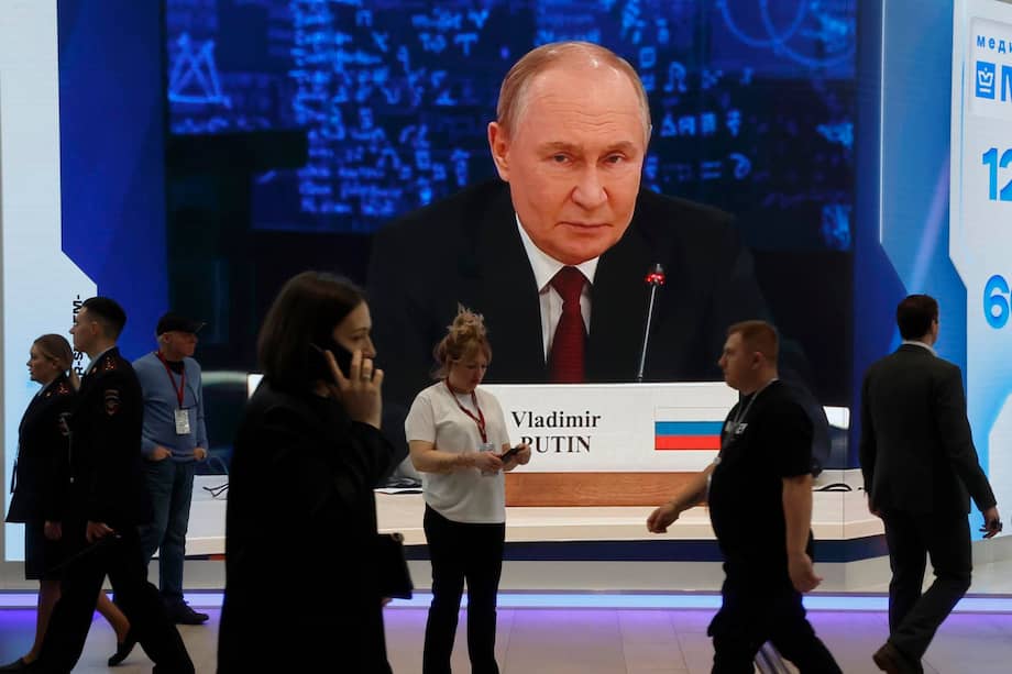 Participantes pasan junto a una gran pantalla que muestra una imagen del presidente ruso, Vladímir Putin, durante el Foro Económico Internacional de San Petersburgo.