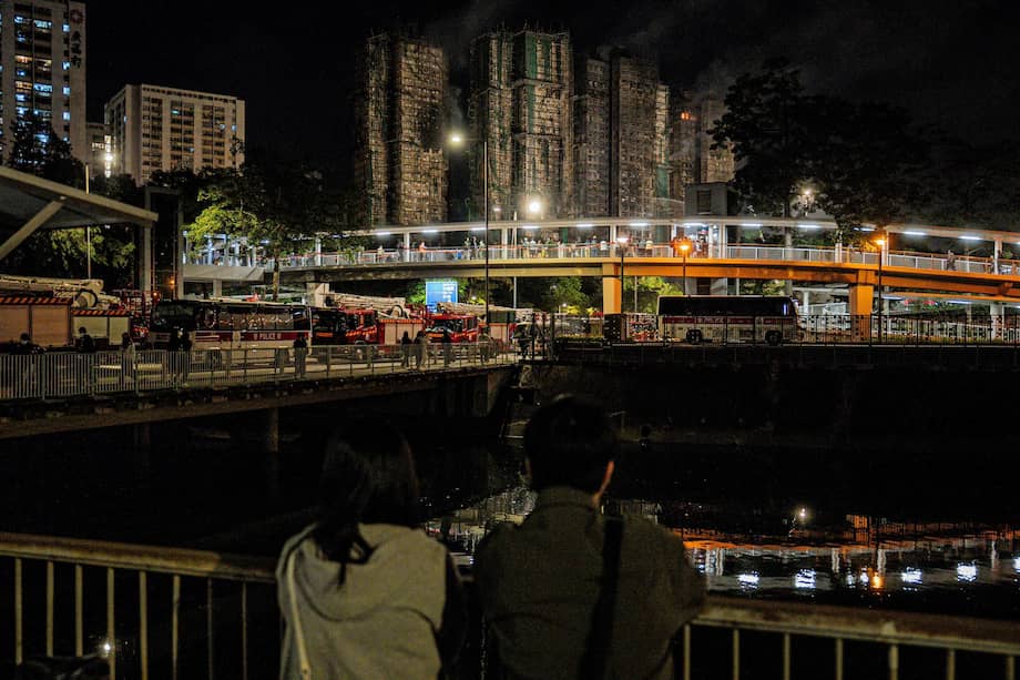 Las personas observan los daños en los edificios tras el incendio de Tai Po, en Hong Kong.