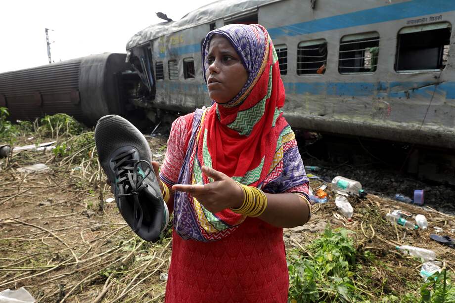 Una mujer muestra un zapato de su hijo desaparecido, encontrado cerca de un compartimento del tren accidentado en Odisha Balasore, India.