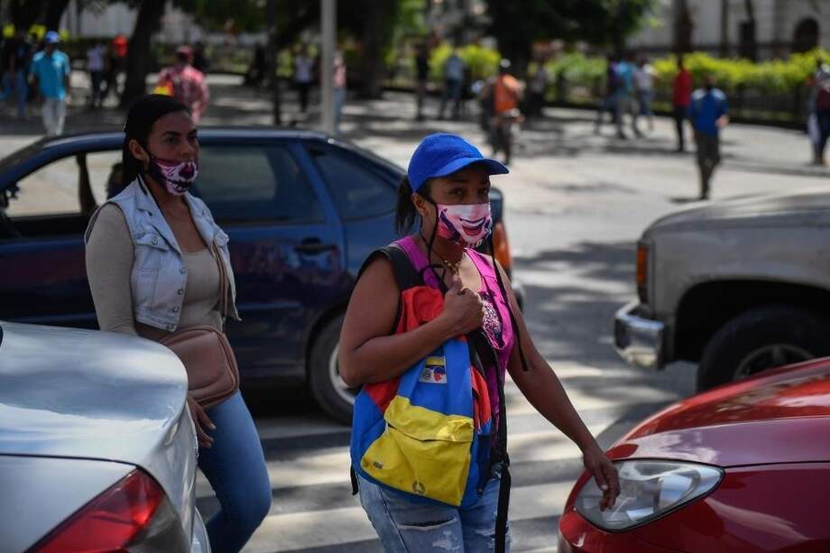 Personas con máscaras protectoras caminan por las calles del centro de Caracas.