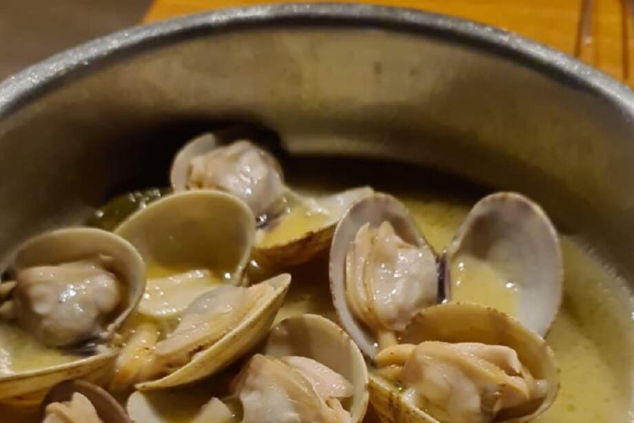 En una olla grande caliente el aceite y saltee el ajo hasta que comience a dorar. Agregue las almejas, el ají, el jerez y la mantequilla.