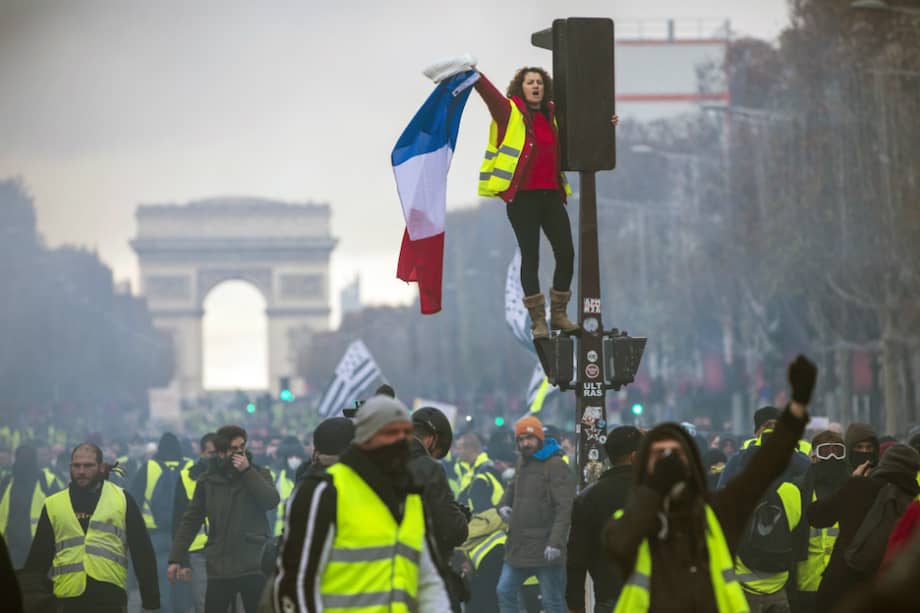 Una mujer, parte de los "chalecos amarillos" grita consignas subida a un semáforo durante una protesta en los Campos Elíseos en París, Francia. / EFE