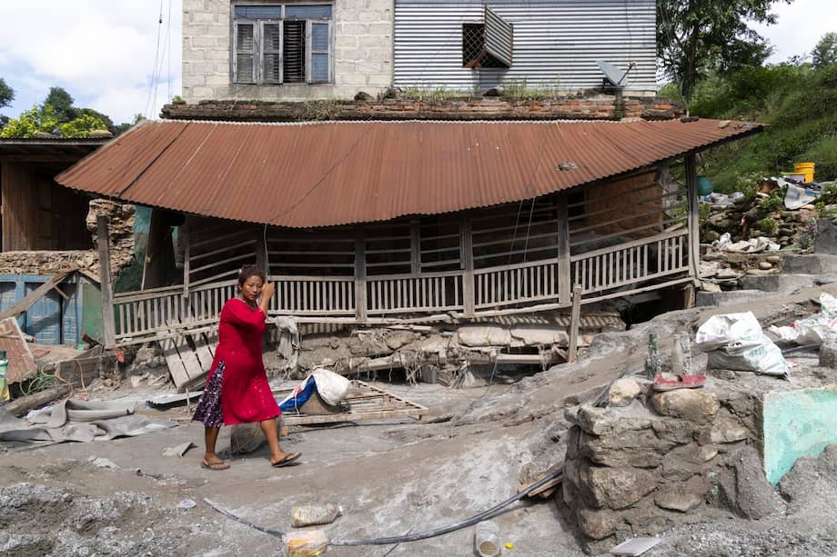 Una mujer camina frente a una vivienda dañada tras las inundaciones repentinas registradas a orillas del río Trishuli, en el distrito de Dhading, Nepal, el 30 de agosto de 2026.