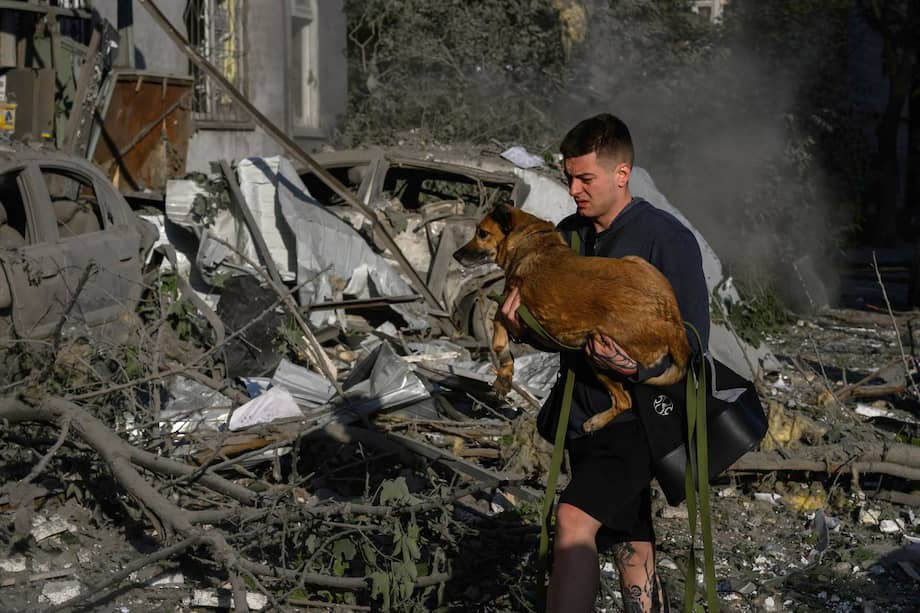 Un hombre carga a un perro mientras escapa de la zona atacada por Rusia en Kiev, Ucrania.