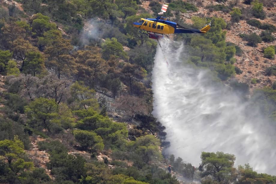 Un helicóptero de extinción de incendios lanza agua sobre un incendio forestal en Agios Sylianos, en la zona de Kouvaras, Ática, Grecia, el 10 de agosto de 2026.