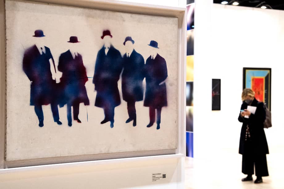 Una mujer pasa cerca de un cuadro del artista italiano Mario Schifano titulado "futuristi" durante una vista previa para la prensa de la primera edición de "Roma Arte en Nuvola", la feria internacional de arte moderno y contemporáneo en Roma. Centro "La Nuvola".