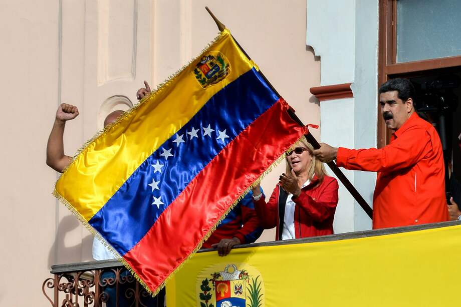 El presidente venezolano, Nicolás Maduro, sostiene una bandera del país mientra se dirige al pueblo desde el Palacio Presidencial de Miraflores. / AFP