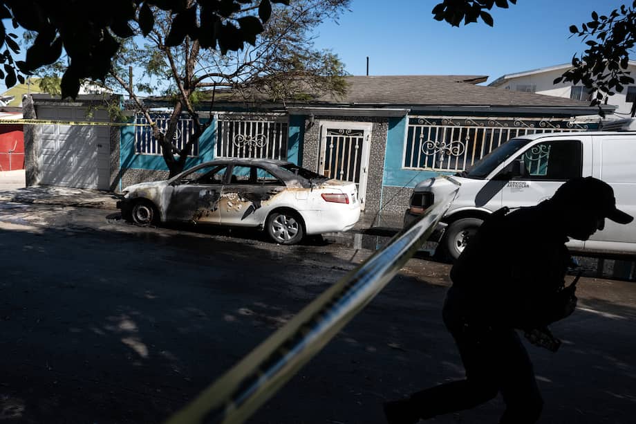 Un policía sale de una zona acordonada después de que un vehículo fue presuntamente incendiado por grupos del crimen organizado en respuesta a un operativo contra Nemesio Oseguera, líder del violento Cartel Jalisco Nueva Generación, en Tijuana, Baja California, México.