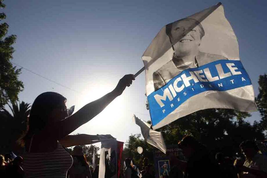 Una mujer en Santiago de Chile sostiene una bandera de apoyo a la candidata Michelle Bachelet, favorita para ganar la contienda electoral de hoy. /EFE