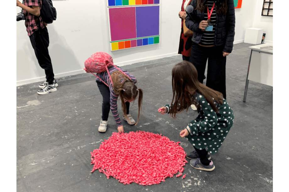 Dos niñas junto a la obra "Placebo Rosa" del artista guatemalteco Esvin Alarcón y que consiste en una montaña de caramelos que se pueden comer, en la Feria Arco. / EFE