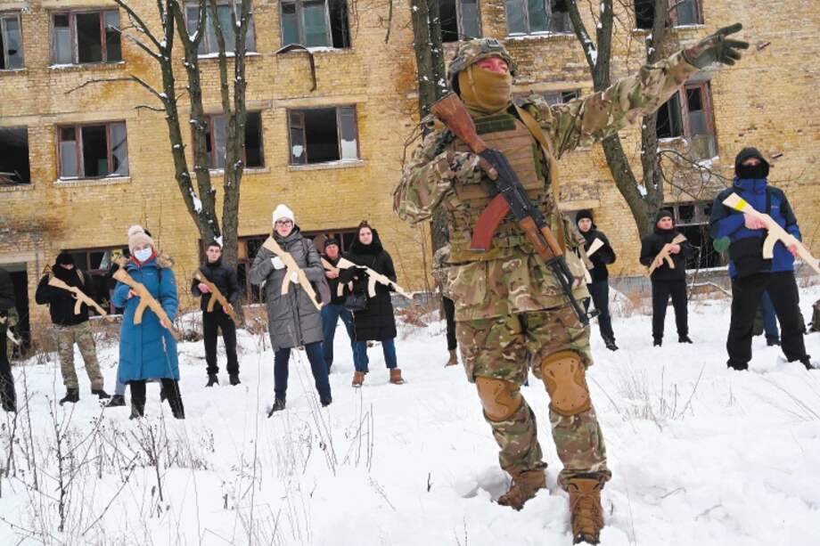 Un instructor militar enseña a civiles que sostienen réplicas de madera de rifles Kalashnikov, durante una sesión de entrenamiento en una fábrica abandonada en la capital ucraniana de Kiev el 30 de enero de 2022.