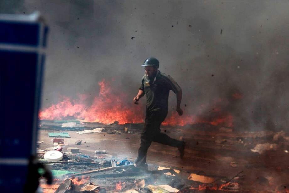 Un manifestante huye de las llamas y el gas lacrimógeno durante una operación llevada a cabo por la policía para desmantelar una de las dos acampadas de los simpatizantes del depuesto presidente Mohamed Mursi. Foto: EFE