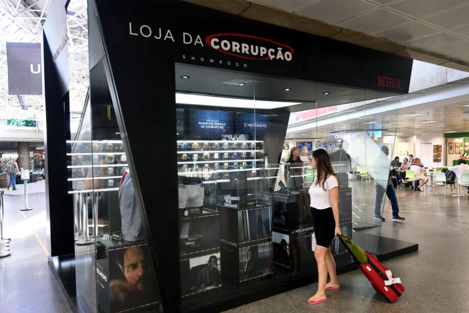 Los pasajeros que acaban de desembarcar se acercan extrañados a la "Loja da corrupção" (tienda de la corrupción) de diseño moderno del aeropuerto internacional de la capital brasileña. / AFP