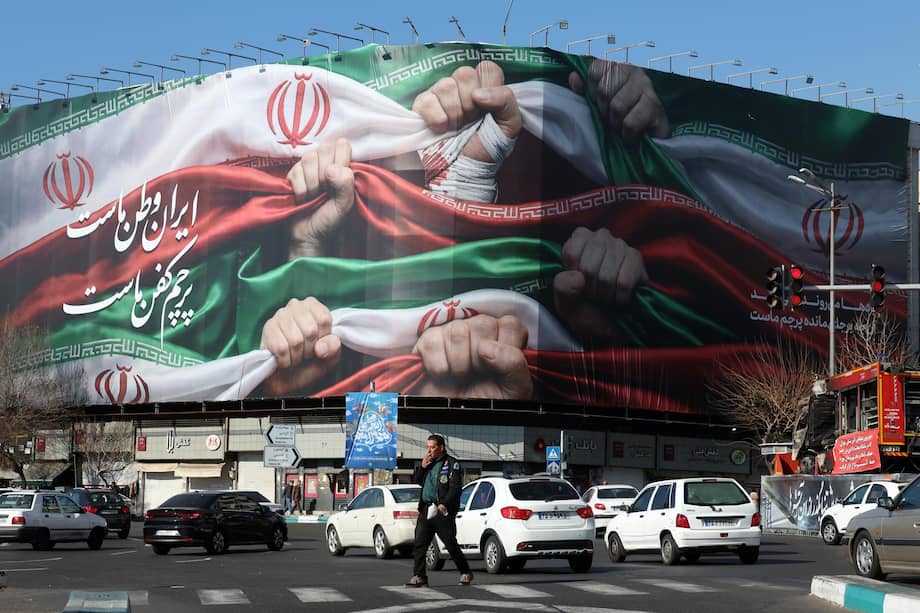 Iraníes caminan junto a un cartel en una tienda que dice en persa "Irán es nuestra patria" en la plaza Enqelab de Teherán.