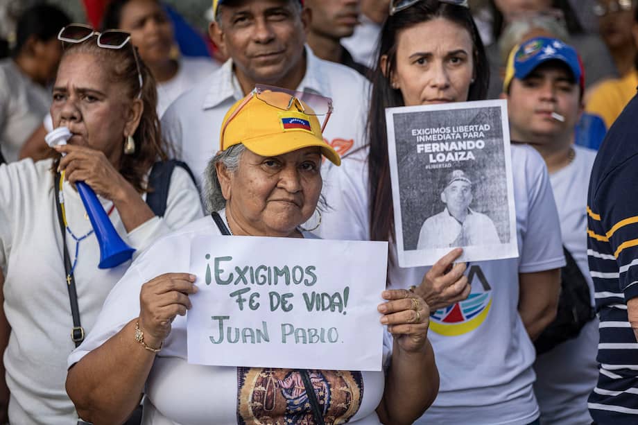Personas sostienen carteles durante una manifestación por la libertad de los presos políticos y del opositor Juan Pablo Guanipa.