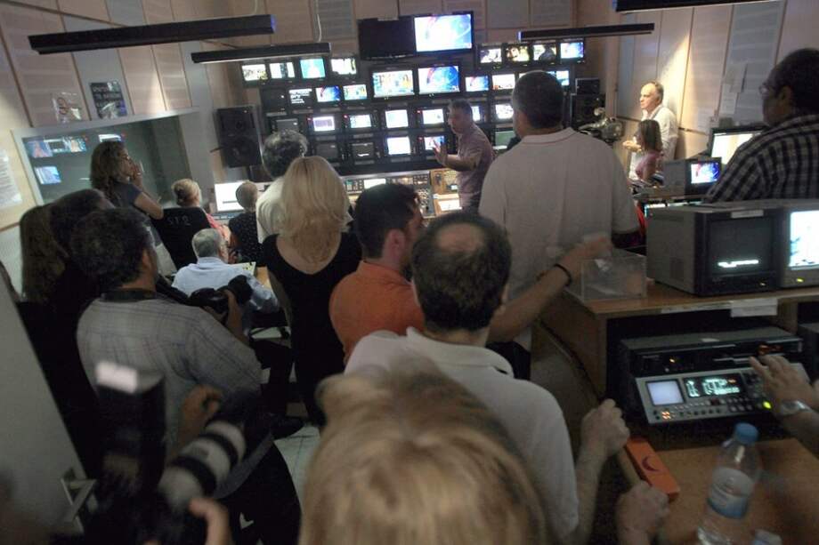 Varios trabajadores de la radiotelevisión pública de Grecia (ERT) escuchan como el gobierno anuncia el cierre de su empresa, en Atenas, Grecia.
