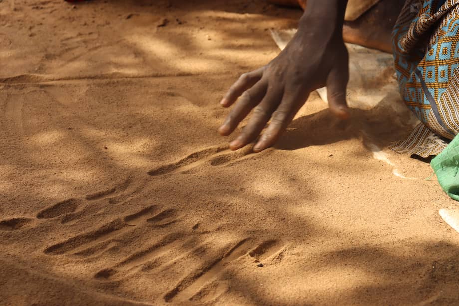 Adama Tandamba se sienta en el suelo de su patio, bajo un árbol y con las piernas cruzadas. Frente a él, arena fina. Es un geomante, también llamado "golpeador de arena". EFE/ Tiga Cheick Sawadogo