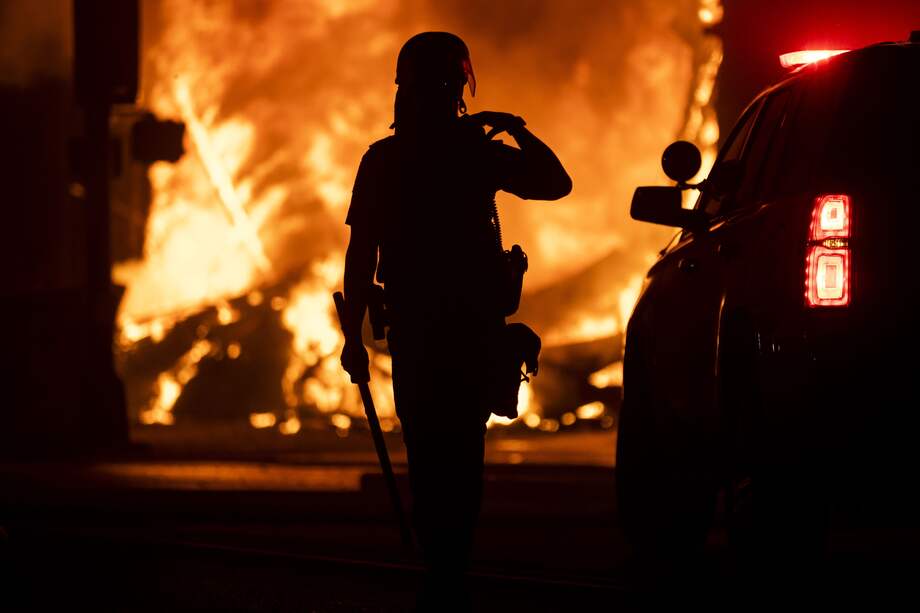 Un oficial de policía vigila mientras una casa de empeño saqueada arde detrás de él el 28 de mayo de 2020 en Minneapolis, Minnesota.