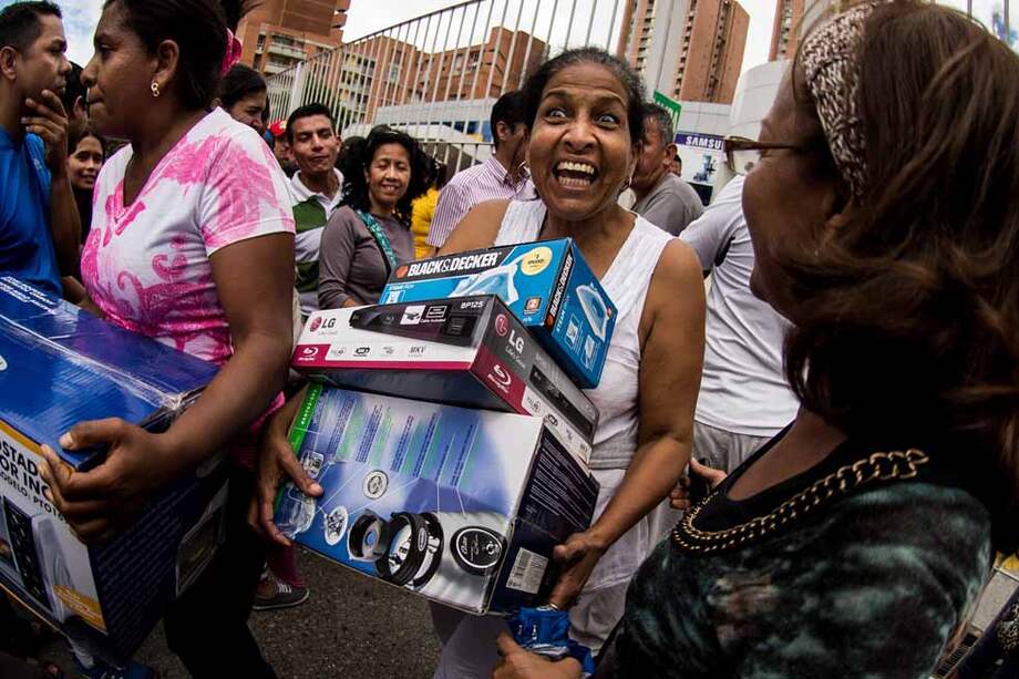 Varias personas salen tras comprar electrodomésticos en una de las sedes de la cadena de tiendas Daka, en Caracas (Venezuela). / AFP