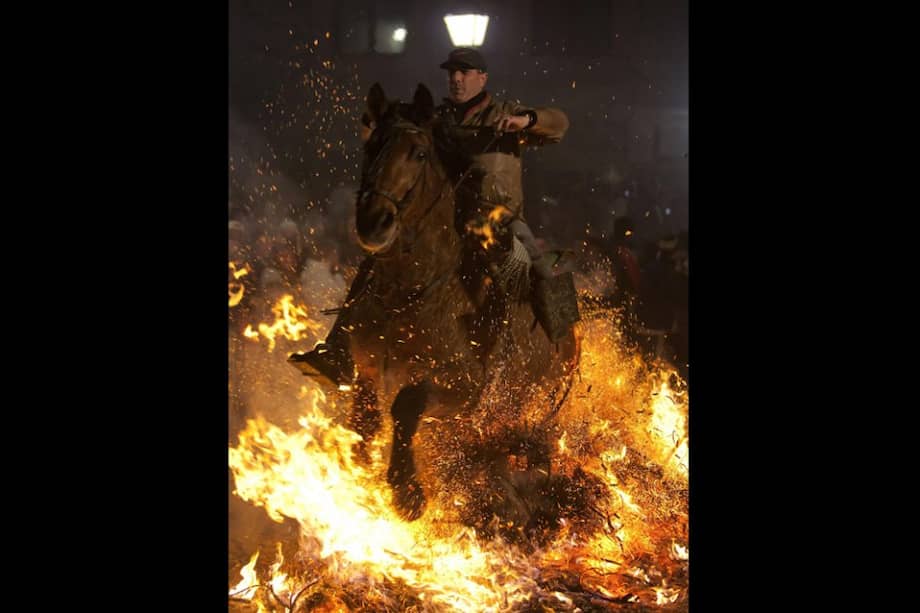 Más de un centenar de caballos, yeguas y burros atraviesa cada una de las hogueras del pueblo para ser purificados por el espeso humo./ EFE