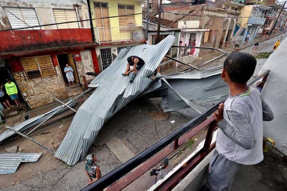 Personas recogen escombros en una calle afectada por el paso del huracán Melissa este miércoles, en Santiago de Cuba (Cuba).