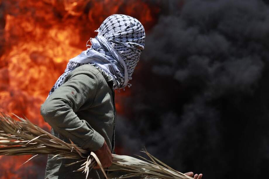 Un manifestante palestino trata de huir de una explosión provocada por una granada de humo, durante una manifestación contra la anexión de partes de Cisjordania por parte de Israel. / EFE