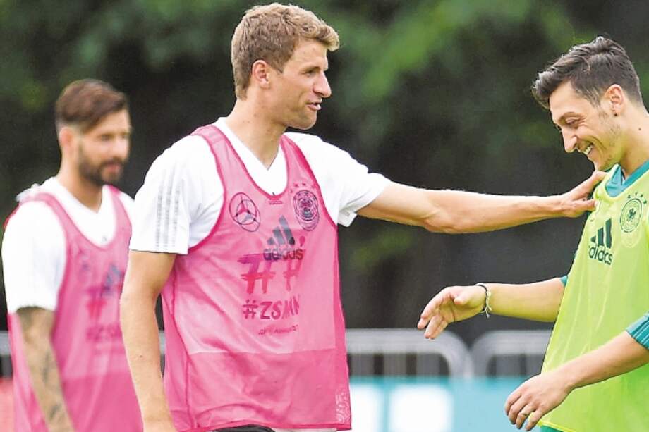 El delantero Thomas Müller conversa con el volante Mesut Özil en la práctica de Alemania, ayer. / AFP