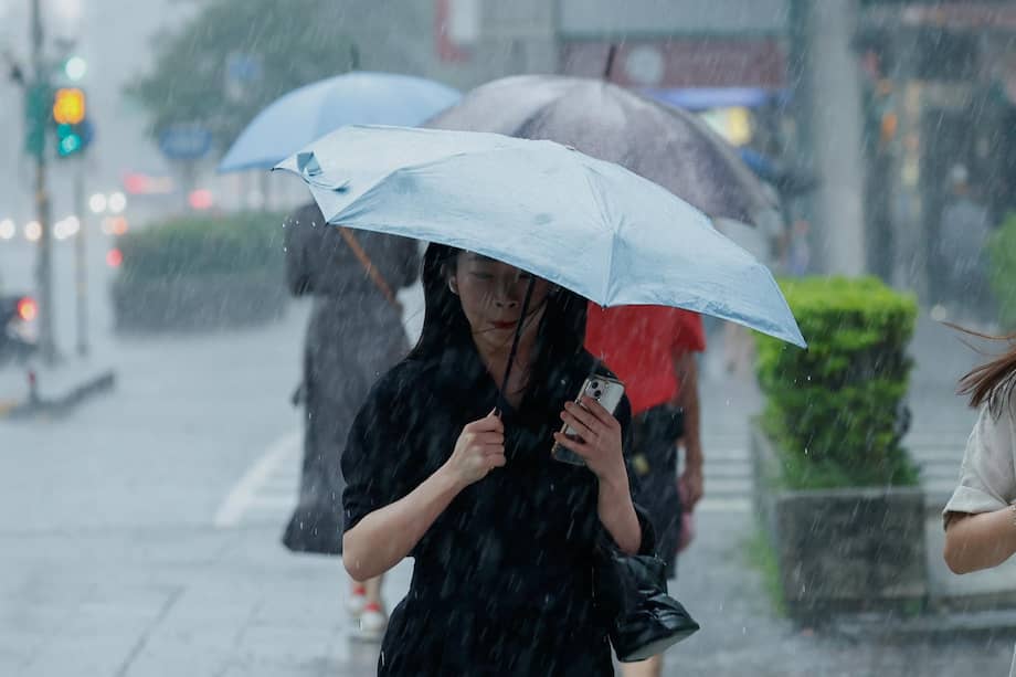 Personas cruzan una calle bajo la fuerte lluvia provocada por el tifón Dolphin en Taipéi, Taiwán, mientras el fenómeno avanzaba hacia China.