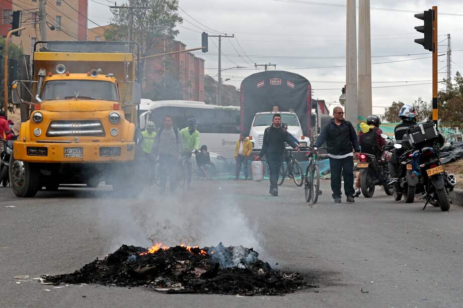 Personas caminan por una vía bloqueada durante una manifestación este jueves en Bogotá (Colombia). Camioneros y conductores de transporte bloquean varias vías de la ciudad para protestar por el incremento en los precios de los combustibles, principalmente el diésel, que comenzó a regir el sábado pasado. EFE/ Carlos Ortega
