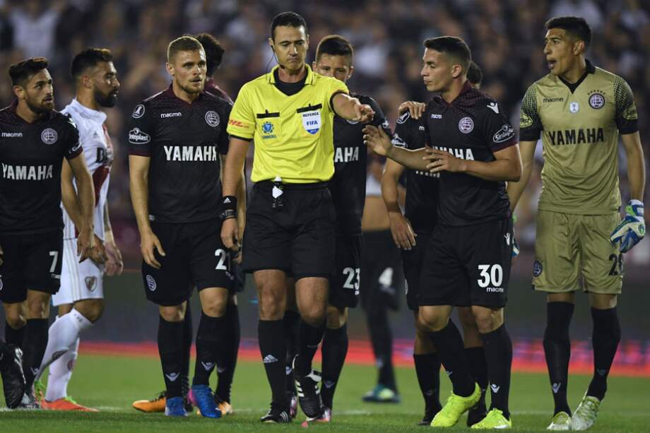 Los jugadores de Lanús le reclaman a Roldán por un penal sancionado a favor de River Plate. / AFP