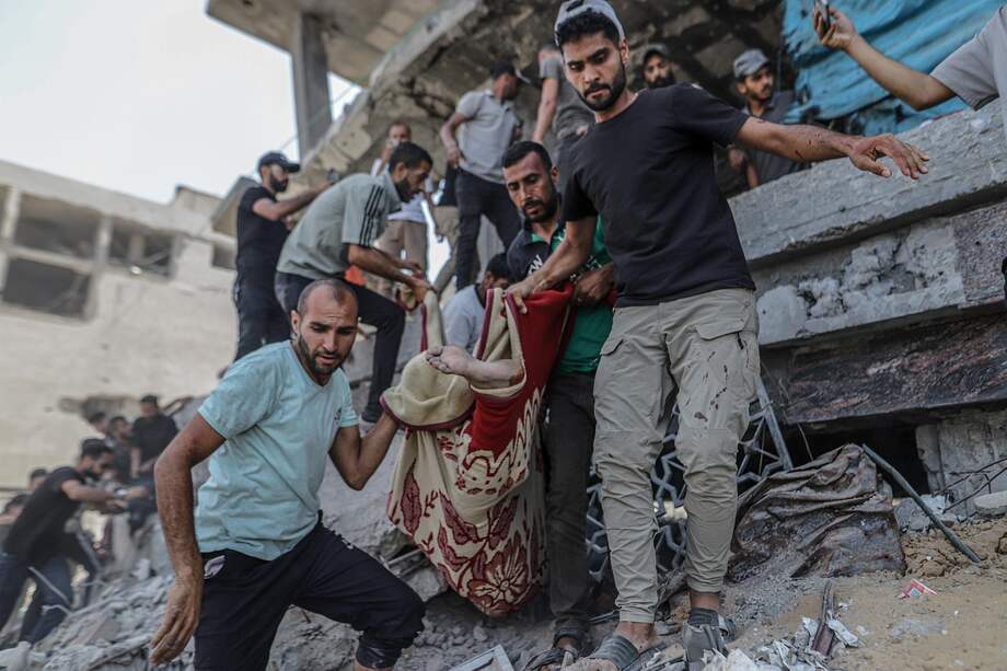 Palestinos desplazados internos recuperan un cuerpo de los escombros de un edificio destruido tras un ataque aéreo israelí en el barrio de Al Remal.