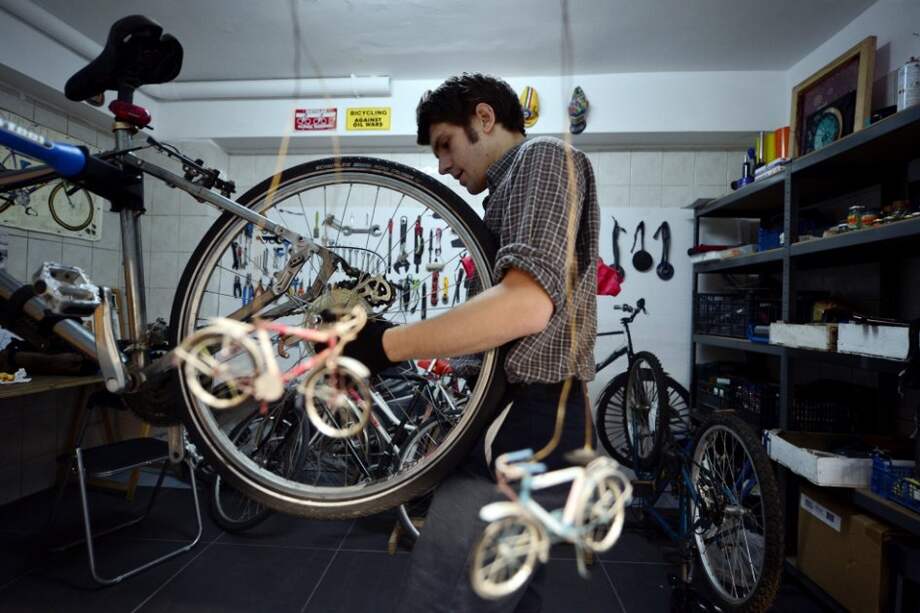 Un joven arregla una bicicleta en un taller de Atenas. El 24,7% de los jóvenes griegos no tienen trabajo ni estudio. / AFP
