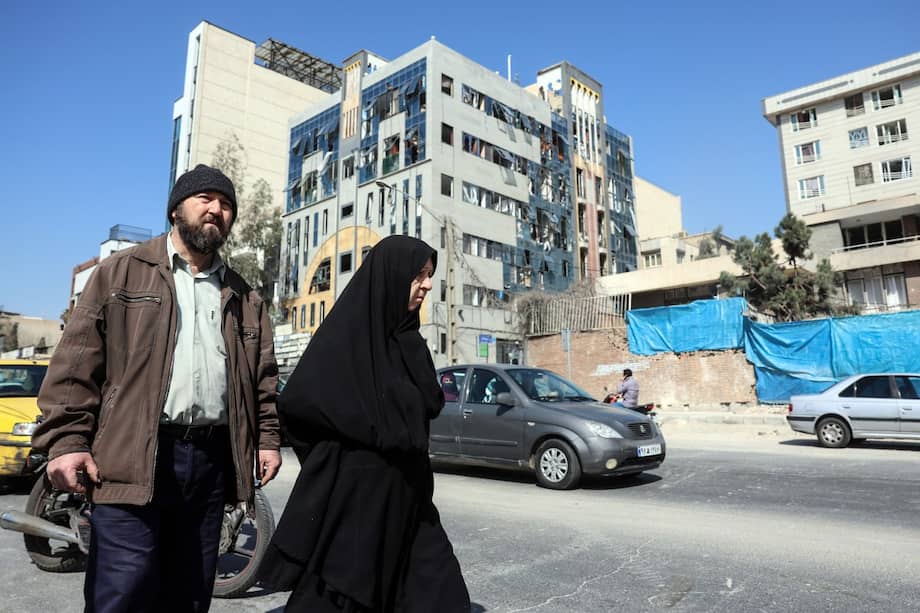 Un hombre y una mujer pasan junto a un edificio dañado tras los ataques aéreos en el centro de Teherán, capital de Irán.