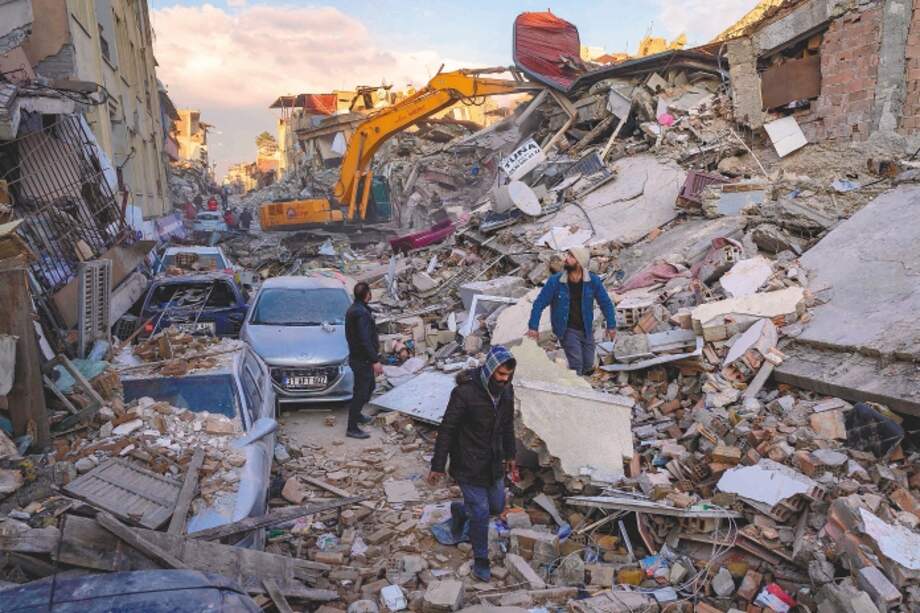 Personas caminan sobre escombros en Antakiya, provincia de Hatay, sur de Turquía.
